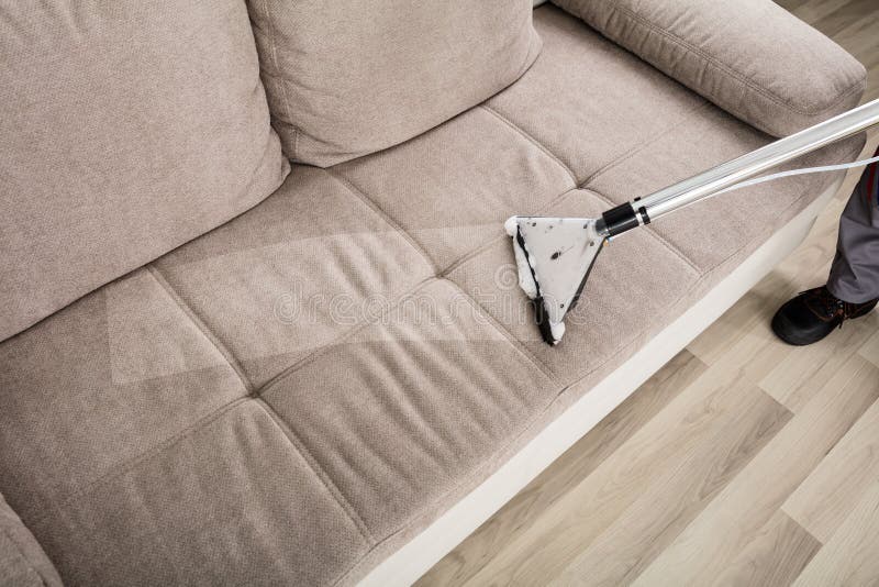 High Angle View Of A Person Cleaning Sofa With Vacuum Cleaner. High Angle View Of A Person Cleaning Sofa With Vacuum Cleaner