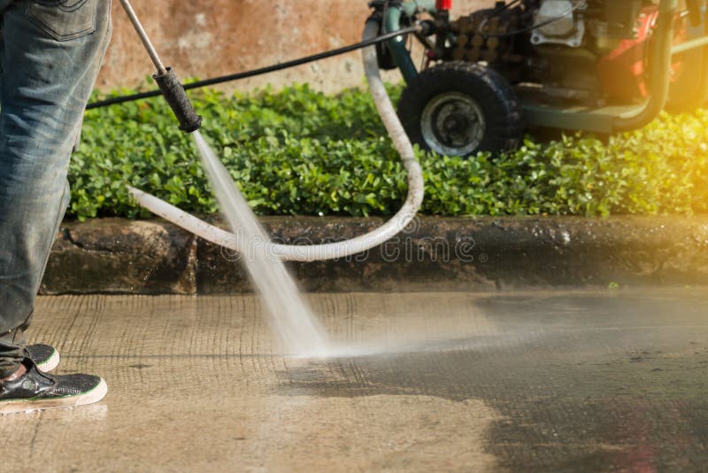 Worker cleaning driveway with gasoline high pressure washer with sunlight . Worker cleaning driveway with gasoline high pressure washer with sunlight .