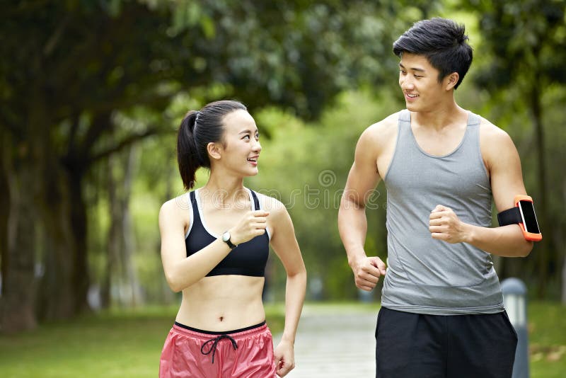 Pulser fonctionnant de jeunes couples asiatiques en parc photo stock Pulser fonctionnant de jeunes couples asiatiques en parc photo stock