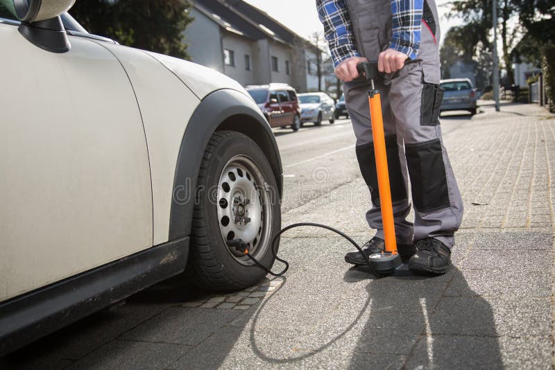 A man is pumping up a car tire after a malfunction. A man is pumping up a car tire after a malfunction