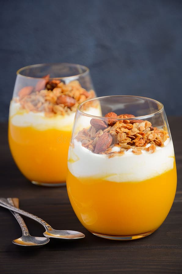 Pumpaefterrätt med yoghurt och hemlagad granola på den mörka trätabellen royaltyfria bilder Pumpaefterrätt med yoghurt och hemlagad granola på den mörka trätabellen royaltyfria bilder