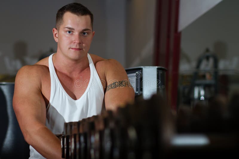 Pumped young man with tattoo in gym