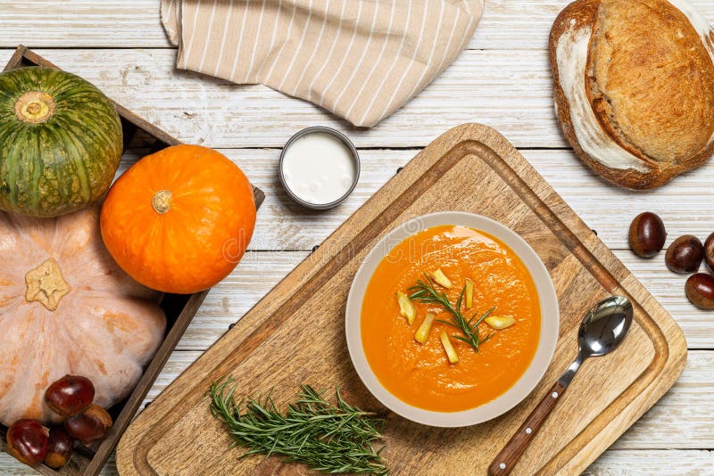Pumpkin and chestnut soup with rosemary twig aside bread loaf, cream, entire pumpkins and chestnuts in a crate on a white wood stock images Pumpkin and chestnut soup with rosemary twig aside bread loaf, cream, entire pumpkins and chestnuts in a crate on a white wood stock images