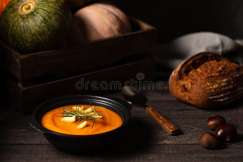 Pumpkin and chestnut soup with rosemary twig aside pumpkins in a crate and chestnuts on a vintage dark wood background royalty free stock photography Pumpkin and chestnut soup with rosemary twig aside pumpkins in a crate and chestnuts on a vintage dark wood background royalty free stock photography