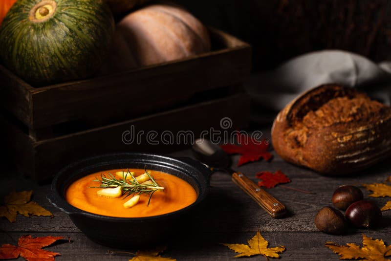 Pumpkin and chestnut soup with rosemary twig aside pumpkins in a crate and chestnuts on a vintage dark wood background with leaves royalty free stock images Pumpkin and chestnut soup with rosemary twig aside pumpkins in a crate and chestnuts on a vintage dark wood background with leaves royalty free stock images