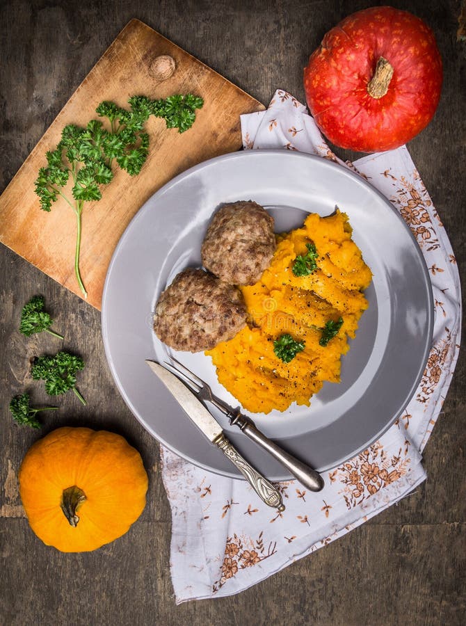 Pumpkin puree with meat patties in plate on old wooden table