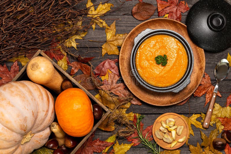 Pumpkin soup aside a spoon and chestnuts pieces on a dark wood background with leaves, wood box with pumpkins royalty free stock images Pumpkin soup aside a spoon and chestnuts pieces on a dark wood background with leaves, wood box with pumpkins royalty free stock images
