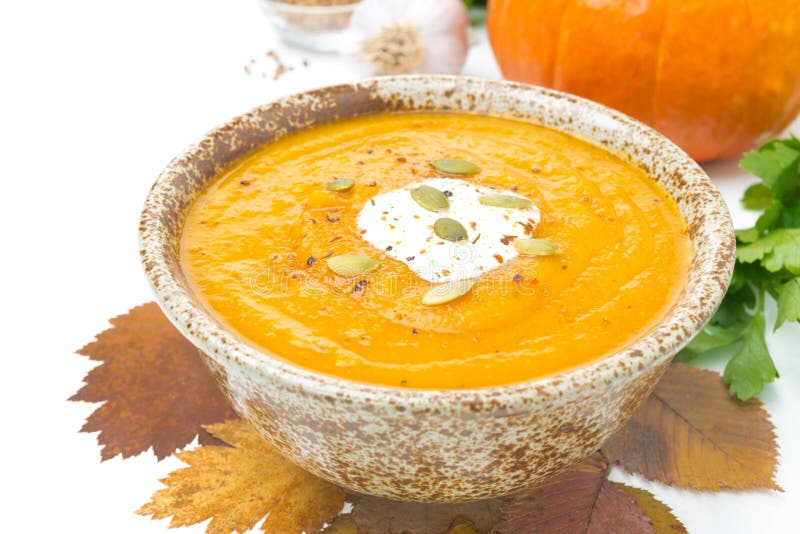 Pumpkin soup with coriander and cream in a bowl, isolated