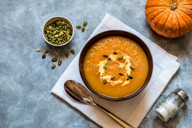 Pumpkin soup with pumpkin seeds and cream on a light background