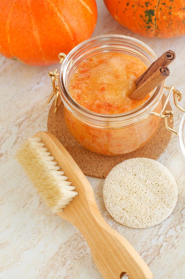 Pumpkin spice scrub with sugar and cinnamon in a glass jar and wooden body brush. Homemade beauty treatment, spa recipe. Pumpkin spice scrub with sugar and cinnamon in a glass jar and wooden body brush. Homemade beauty treatment, spa recipe