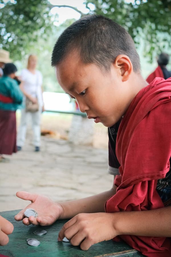 Punakha, Bhutan - 11 septembre 2016 : Jeune moine de Bhutanase comptant des pièces de monnaie sur sa main dans un monastère au Bh photos stock Punakha, Bhutan - 11 septembre 2016 : Jeune moine de Bhutanase comptant des pièces de monnaie sur sa main dans un monastère au Bh photos stock
