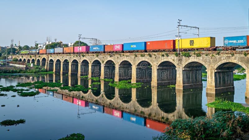 Pune maharashtra indiajun 1 2023 : un tren de containere colorat care trece peste pod cu o reflexie plăcută în apa râului royalty free stock images