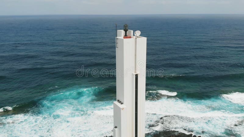 Punta del Hidalgo, Espanha - 22 de abril de 2019: Belo farol branco na costa do oceano Atlântico, dia ensolarado imagem de stock Punta del Hidalgo, Espanha - 22 de abril de 2019: Belo farol branco na costa do oceano Atlântico, dia ensolarado imagem de stock