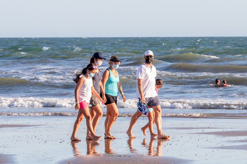 Punta Umbria, Huelva, Spain - August 2, 2020: A family walking by the beach wearing protective or medical face masks. New normal