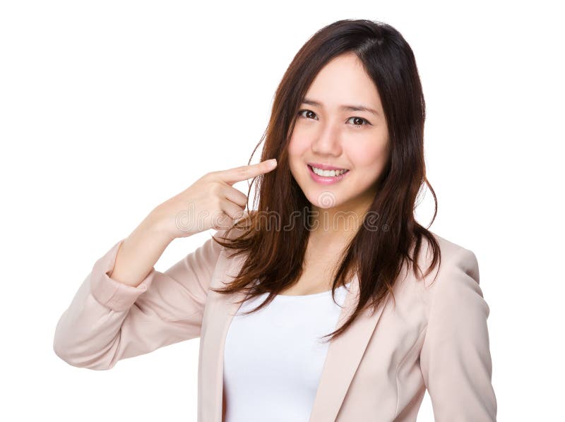 Punto del dito della donna di affari ai suoi denti fotografia stock Punto del dito della donna di affari ai suoi denti fotografia stock
