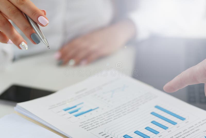 Punto di penna femminile dell'argento della tenuta del braccio nel grafico finanziario fotografie stock libere da diritti Punto di penna femminile dell'argento della tenuta del braccio nel grafico finanziario fotografie stock libere da diritti
