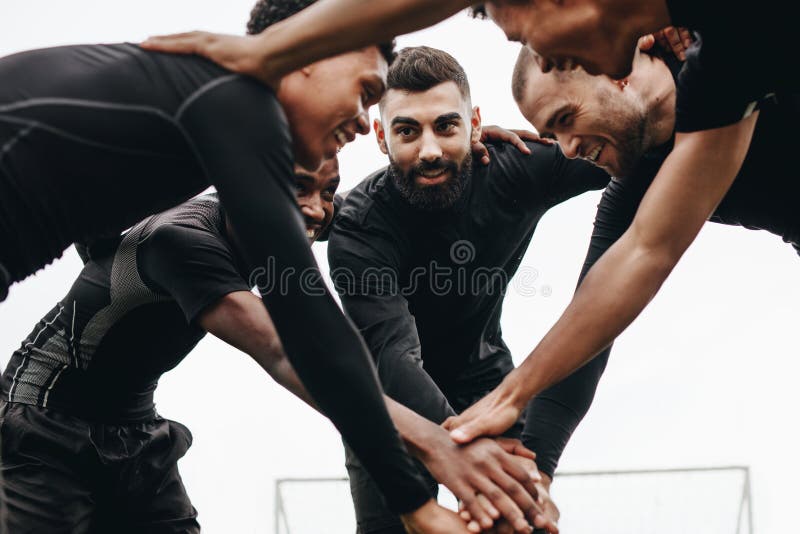 Punto di vista di angolo basso dei calciatori che parlano della condizione del piano tattico in una calca Calciatori che tengono immagine stock libera da diritti Punto di vista di angolo basso dei calciatori che parlano della condizione del piano tattico in una calca Calciatori che tengono immagine stock libera da diritti