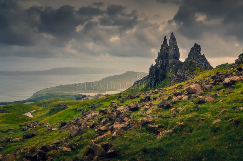 Punto di vista del paesaggio dell'uomo anziano di formazione rocciosa di Storr, nuvole drammatiche, Scozia immagine stock libera da diritti Punto di vista del paesaggio dell'uomo anziano di formazione rocciosa di Storr, nuvole drammatiche, Scozia immagine stock libera da diritti
