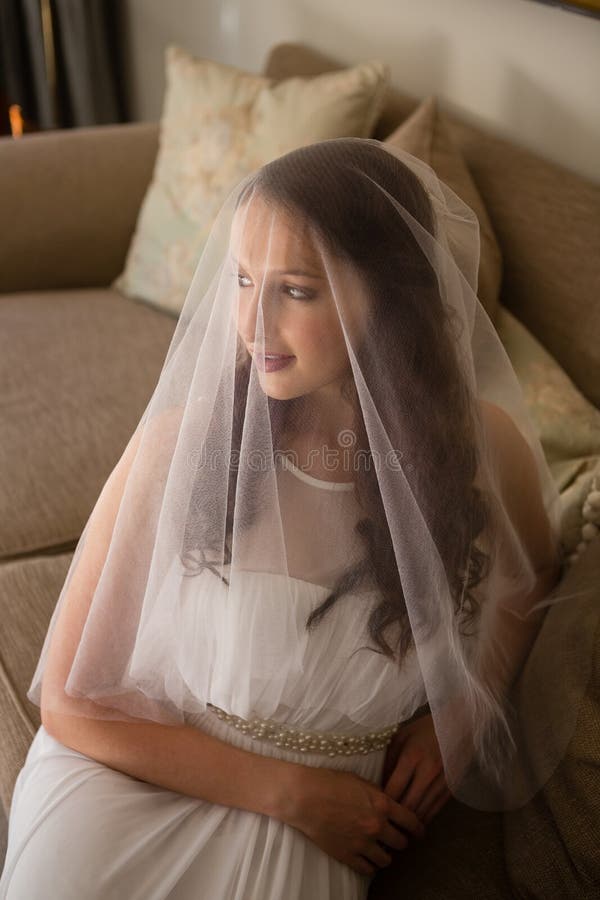 Punto di vista dell'angolo alto di bella sposa in vestito da sposa che si siede sul sofà immagini stock libere da diritti Punto di vista dell'angolo alto di bella sposa in vestito da sposa che si siede sul sofà immagini stock libere da diritti
