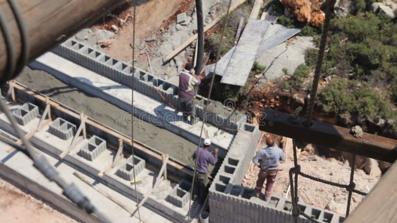 Punto di vista dell'angolo alto dei muratori che versano calcestruzzo nel cantiere