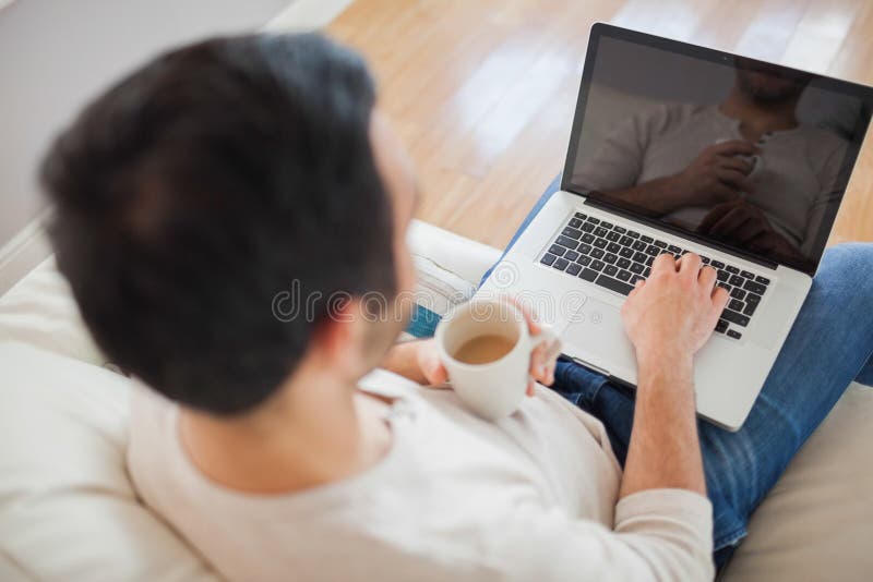Punto di vista dell'angolo alto del giovane che per mezzo del suo computer portatile fotografia stock libera da diritti Punto di vista dell'angolo alto del giovane che per mezzo del suo computer portatile fotografia stock libera da diritti