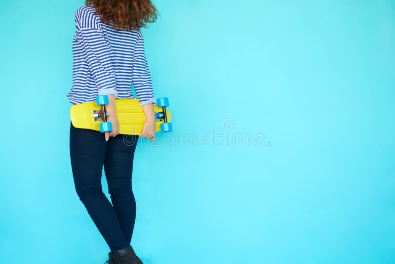 Punto di vista posteriore del pattinatore funky della donna con il suo pattino giallo fotografie stock libere da diritti Punto di vista posteriore del pattinatore funky della donna con il suo pattino giallo fotografie stock libere da diritti