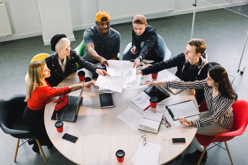 Punto di vista superiore dei giovani creativi multirazziali in ufficio moderno Il gruppo di gente di affari sta collaborando con fotografia stock Punto di vista superiore dei giovani creativi multirazziali in ufficio moderno Il gruppo di gente di affari sta collaborando con fotografia stock