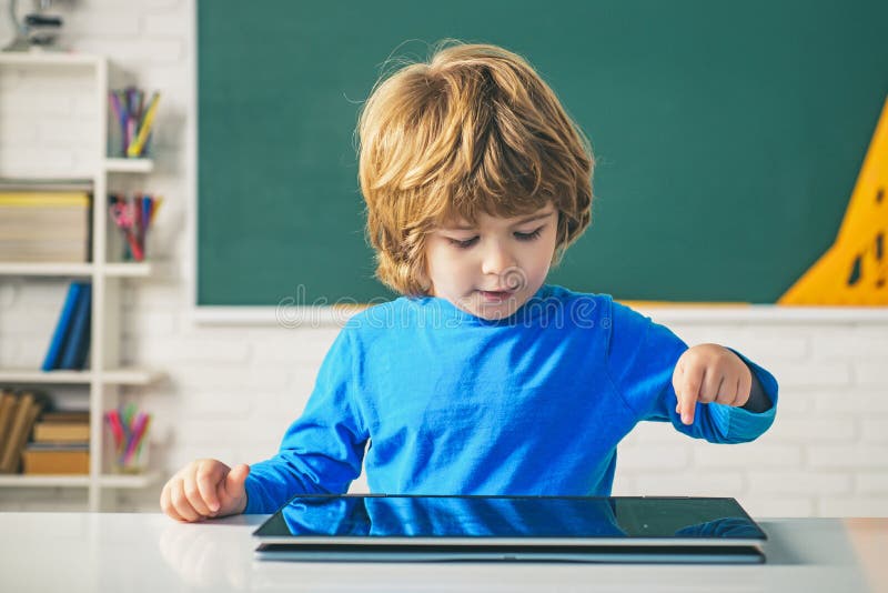 Pupil in class using digital tablet. Schoolboy with digital tablet in school classroom. Educational process. royalty free stock images