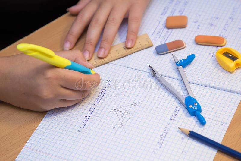 Pupil&#x27;s hand in close-up solve a geometry problem in a notebook. stock image