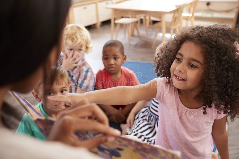 Pupils At Montessori School Looking At Book With Teacher royalty free stock photography Pupils At Montessori School Looking At Book With Teacher royalty free stock photography