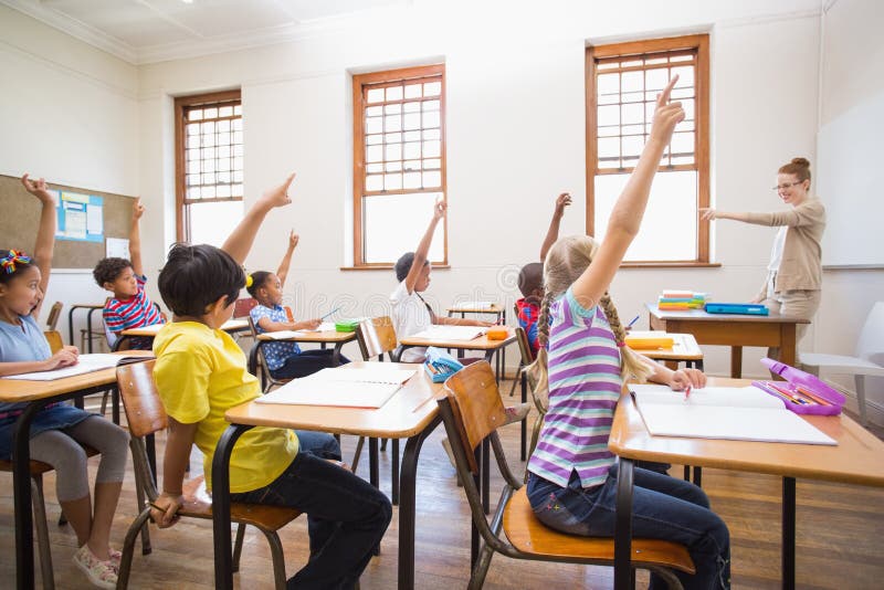 Pupils raising hand in classroom stock images