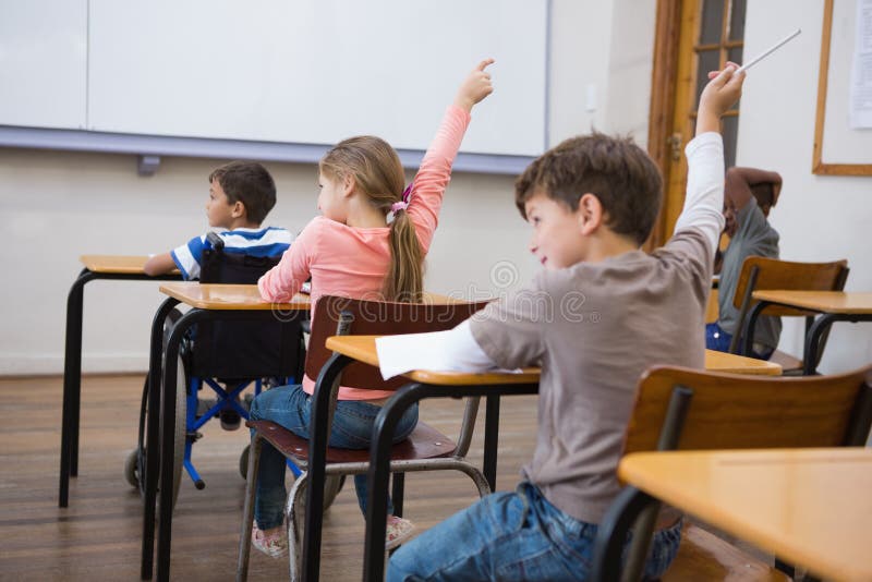 Pupils raising their hands during class stock image