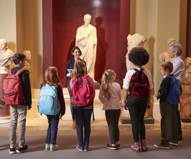 Pupils And Teacher On School Field Trip To Museum With Guide