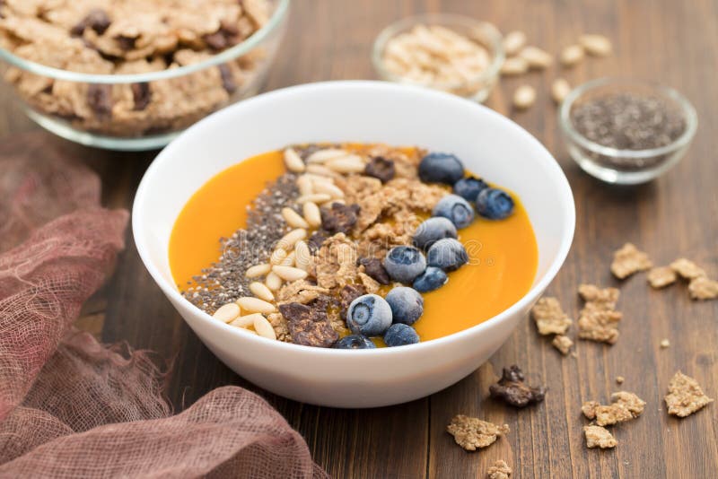 Puree van mango met granola, chia en bessen in witte kom stock afbeelding Puree van mango met granola, chia en bessen in witte kom stock afbeelding