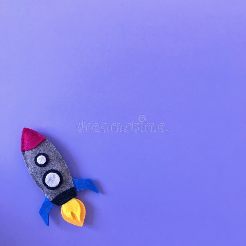 Purple background with small rocket toy hand made from felt fabric. Colorful handmade toy flat lay. Colorful crafting supplies space ship top view photography from above with copy space, text area, spaceship, universe, galaxy, cosmos, missile, texture, blue, bright, happy, colors, template, banner, square, header, diy, project, crafts, art, boys, children, theme, announcement, card, creation, creative, inspiration, idea, isolated, baby, crib, mobile, nursery, ornament, modern. Purple background with small rocket toy hand made from felt fabric. Colorful handmade toy flat lay. Colorful crafting supplies space ship top view photography from above with copy space, text area, spaceship, universe, galaxy, cosmos, missile, texture, blue, bright, happy, colors, template, banner, square, header, diy, project, crafts, art, boys, children, theme, announcement, card, creation, creative, inspiration, idea, isolated, baby, crib, mobile, nursery, ornament, modern