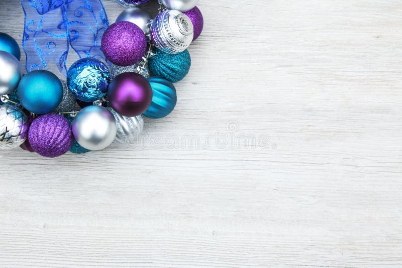 Purple, blue, and silver christmas ball ornaments on a wooden ba