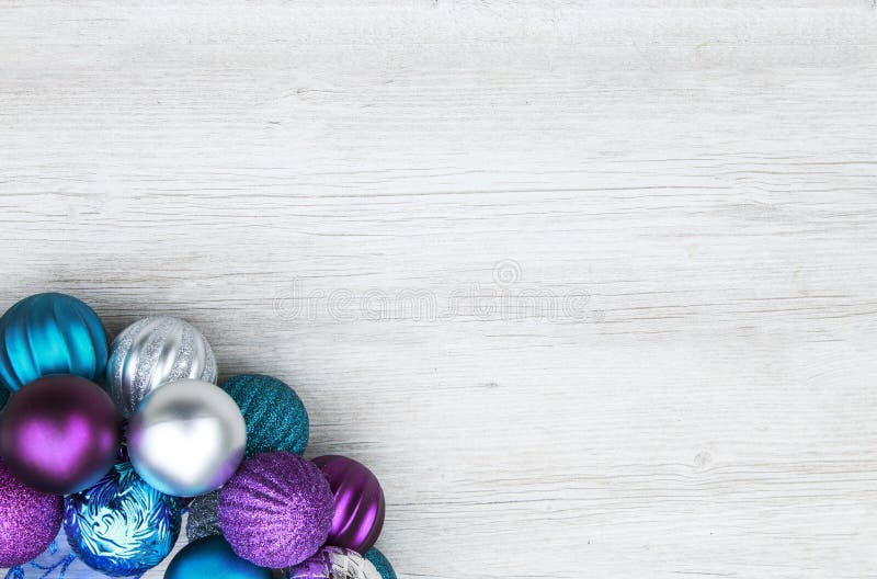 Purple, blue, and silver christmas ball ornaments on a wooden ba