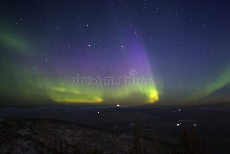 Viola-verde-giallastro aurora boreale nel cielo stellato sopra collina terreno litted con il chiaro di luna.