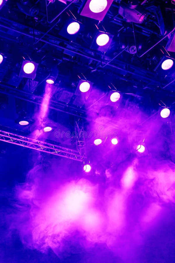 Purple light rays from the spotlight through the smoke at the theater or concert hall. Lighting equipment for a performance