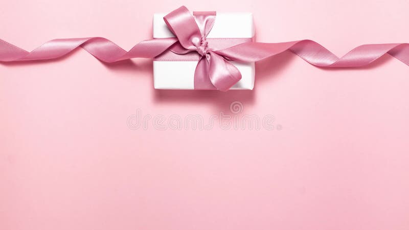 Purple ribbon tied in a gift bow on white gift box on pink background with copy space. Stop motion animation