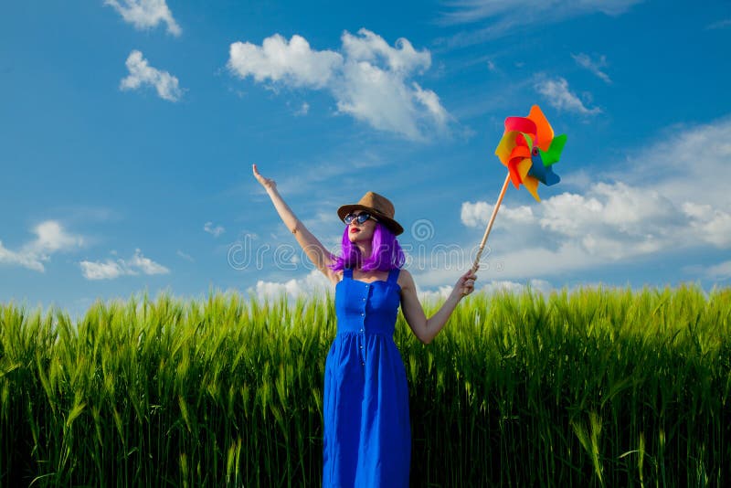 Purpurowa włosiana dziewczyna z pinwheel przy pszenicznym polem zdjęcia stock Purpurowa włosiana dziewczyna z pinwheel przy pszenicznym polem zdjęcia stock