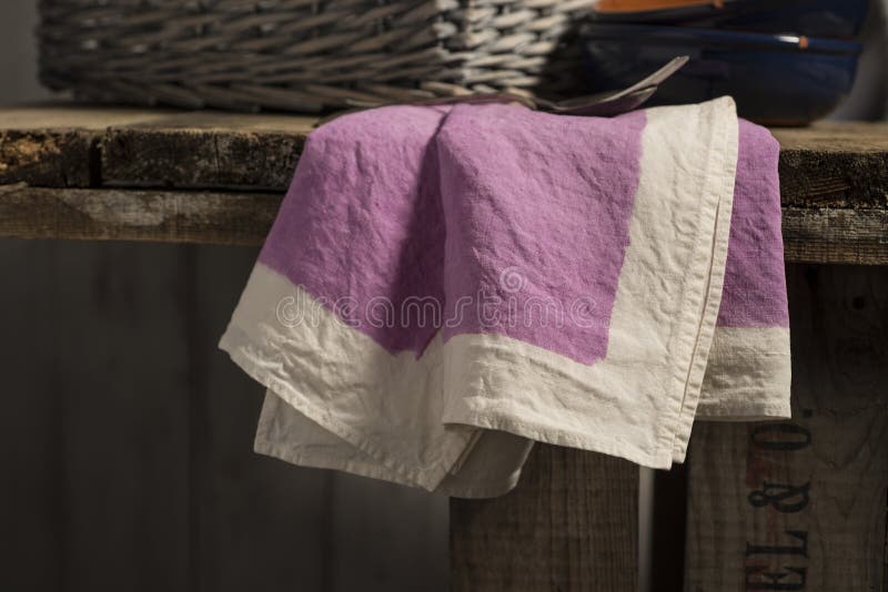 Purpurrote Tafelserviette, die vom Rand des Holztischs baumelt lizenzfreie stockfotos Purpurrote Tafelserviette, die vom Rand des Holztischs baumelt lizenzfreie stockfotos