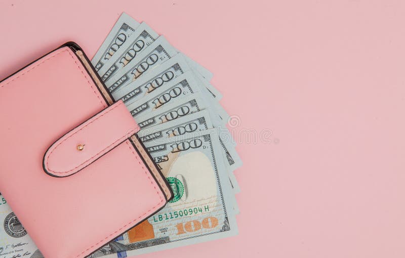 Purse with one hundred dollars banknotes on pink background. Flat lay, top view, copy space