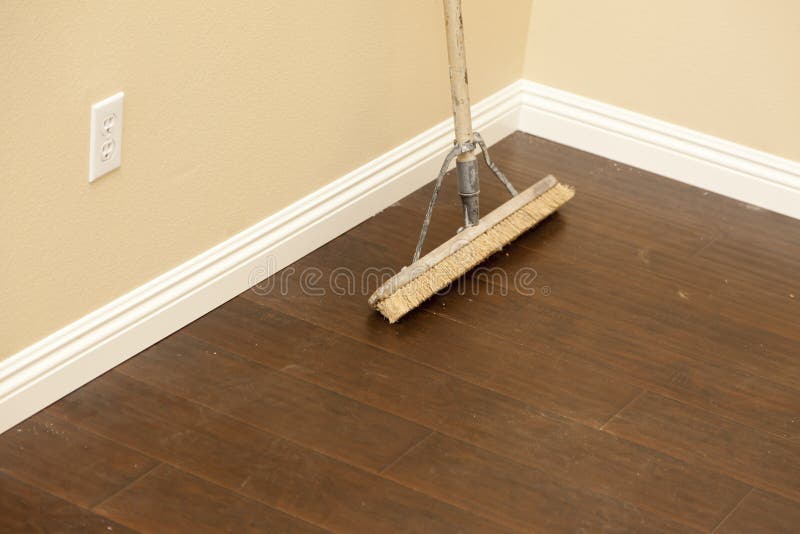 Push Broom on a Newly Installed Laminate Floor and Baseboard royalty free stock photography