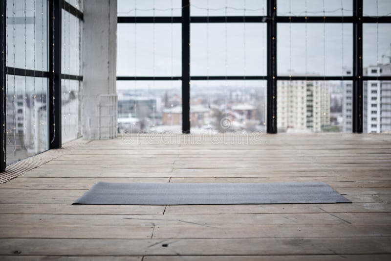 Empty space in fitness center, big windows, natural wooden floor, modern loft studio, unrolled yoga mat on the floor. no people. Empty space in fitness center, big windows, natural wooden floor, modern loft studio, unrolled yoga mat on the floor. no people