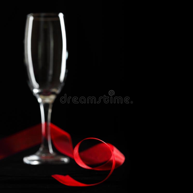 Empty champagne glass with red organza ribben perfect for gift card or celebration. Shallow depth of field. Empty champagne glass with red organza ribben perfect for gift card or celebration. Shallow depth of field