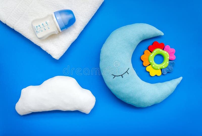 Baby care concept with moon pillow, clouds, feeding bottle and toy for sleep of newborn on blue background top view stock image Baby care concept with moon pillow, clouds, feeding bottle and toy for sleep of newborn on blue background top view stock image