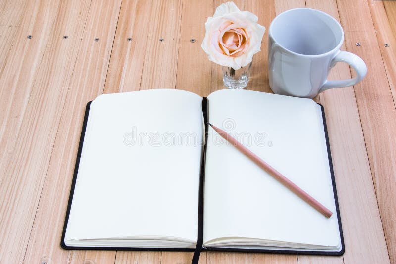 Put pencil on notebook near cup of coffee and rose