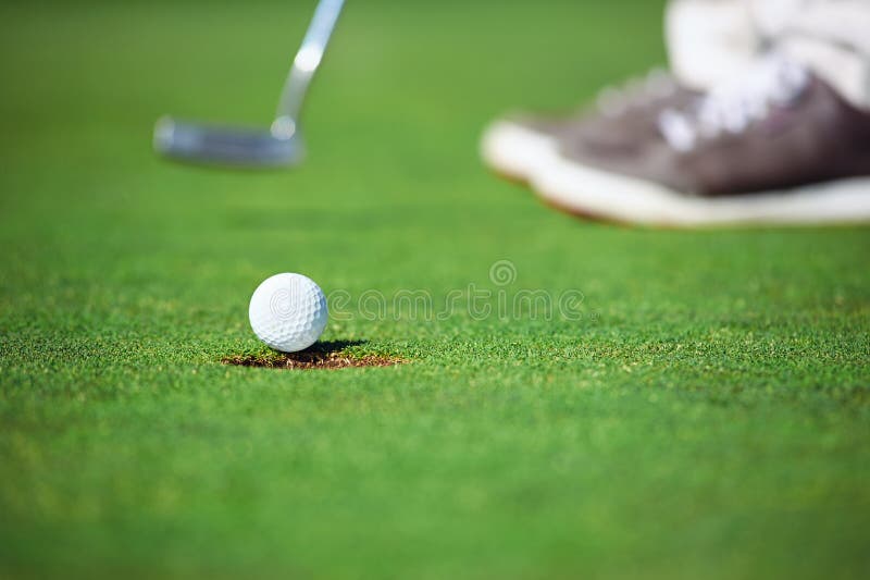 Golf ball falling into hole after putt on green. Golf ball falling into hole after putt on green