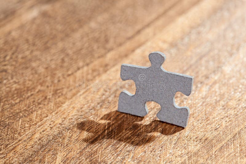 Jigsaw puzzle piece in a shape o f a man on a table. Shallow depth of field. Jigsaw puzzle piece in a shape o f a man on a table. Shallow depth of field